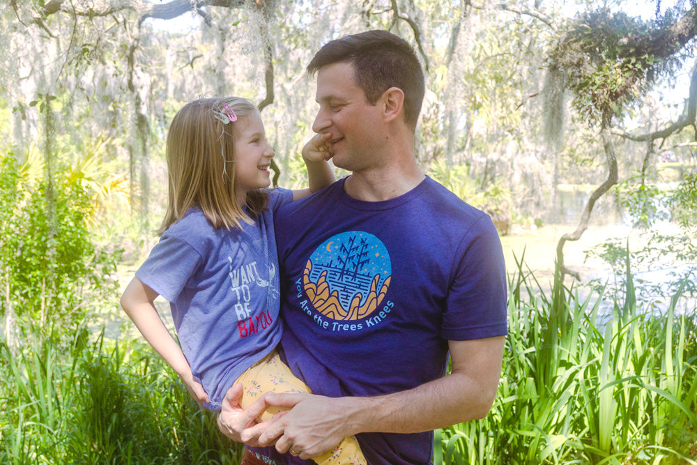 Dad and daughter, dad in a Heartsleeve trees knees shirt and daughter in a Heartsleeve Bayou shirt