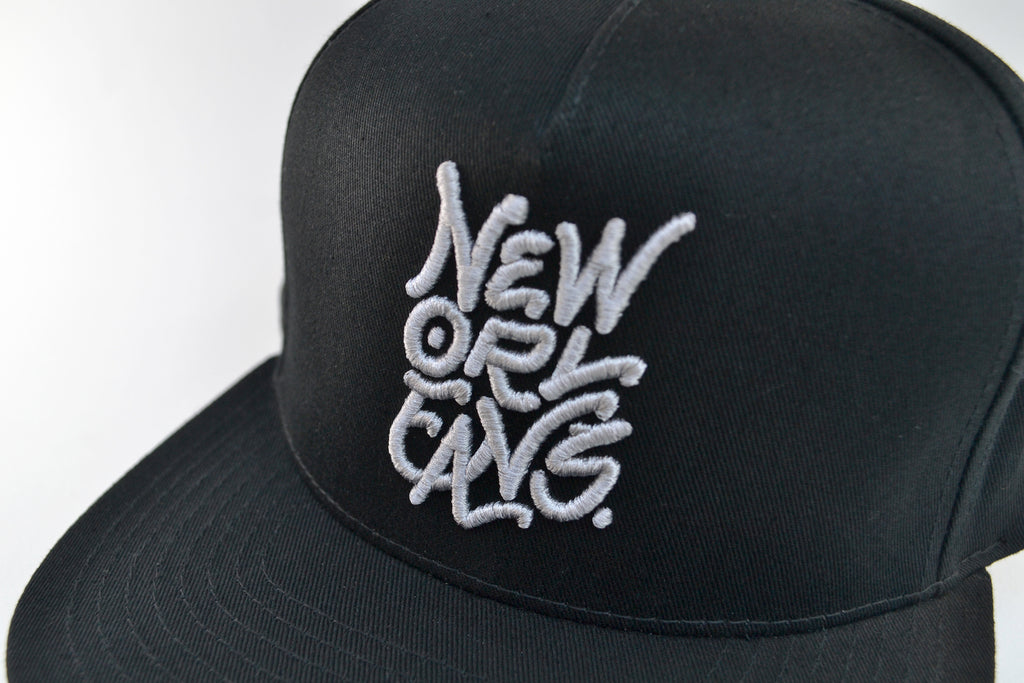 Black flat brim hat with New Orleans embroidered across front in grey thread.